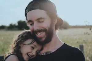 A joyful dad and daughter sharing a fun moment together, embodying how to be more happy through laughter and connection.